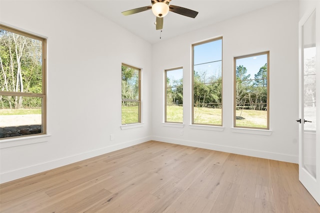 spare room with a healthy amount of sunlight, light wood-style flooring, baseboards, and a ceiling fan