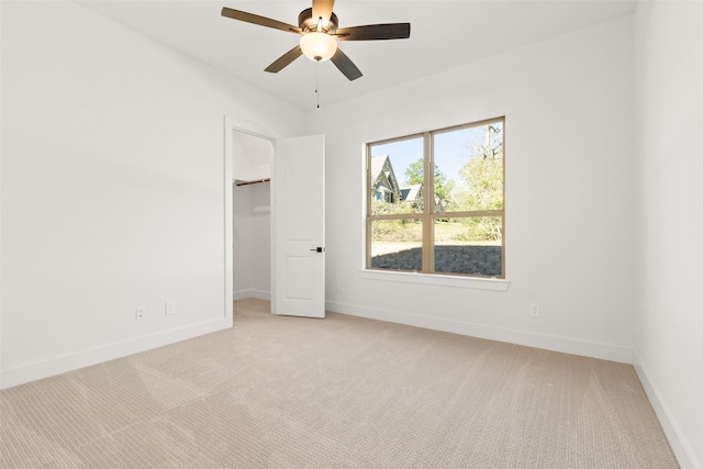 empty room with a ceiling fan, light colored carpet, and baseboards