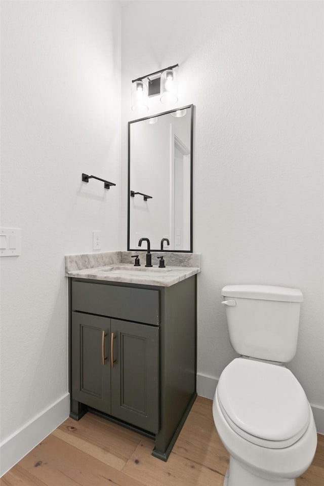 bathroom featuring baseboards, vanity, toilet, and wood finished floors