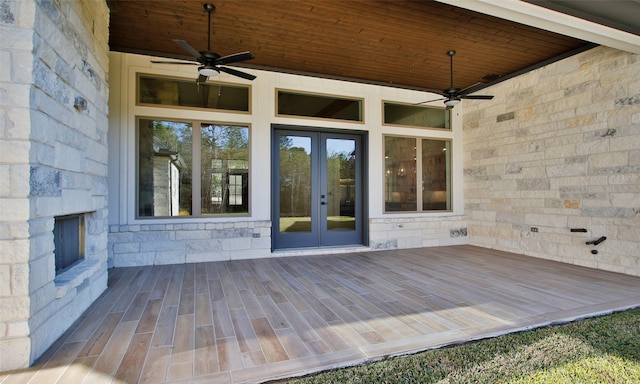 wooden terrace with french doors, an outdoor stone fireplace, and ceiling fan