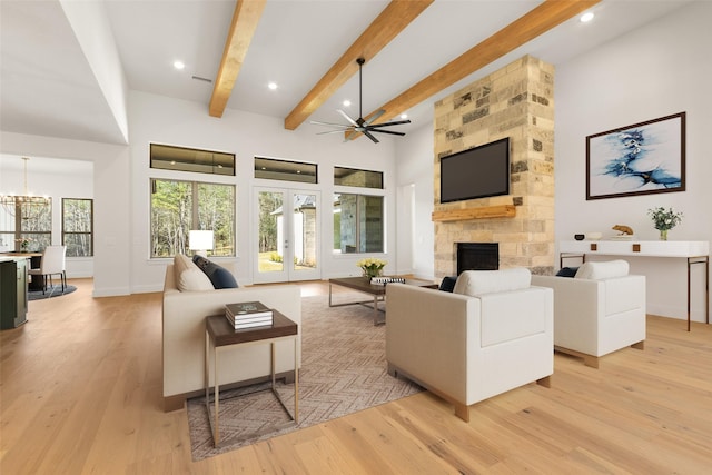 living area with french doors, a stone fireplace, beamed ceiling, and light wood-style floors