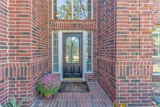 view of exterior entry featuring brick siding