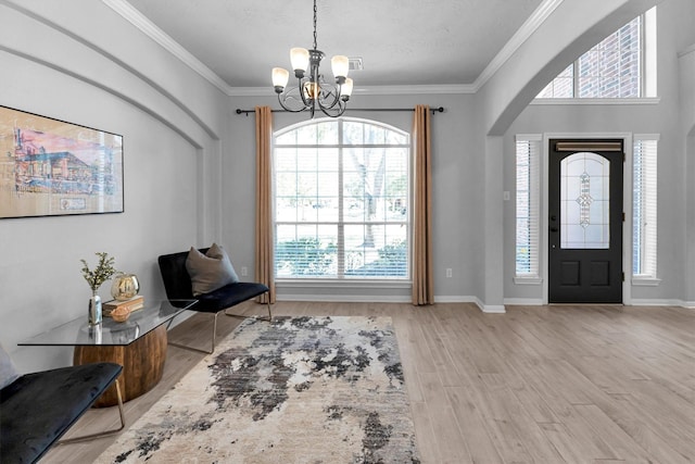 foyer with baseboards, arched walkways, an inviting chandelier, crown molding, and light wood-style floors