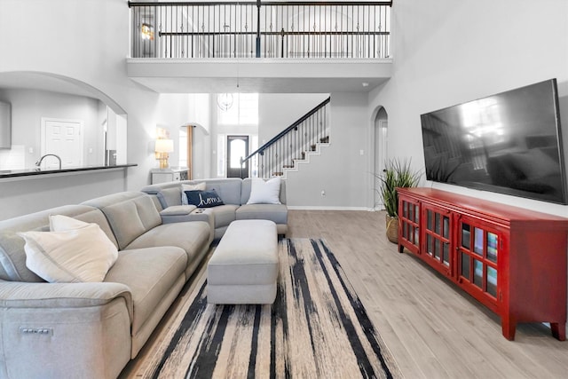 living room featuring a towering ceiling, light wood finished floors, and arched walkways