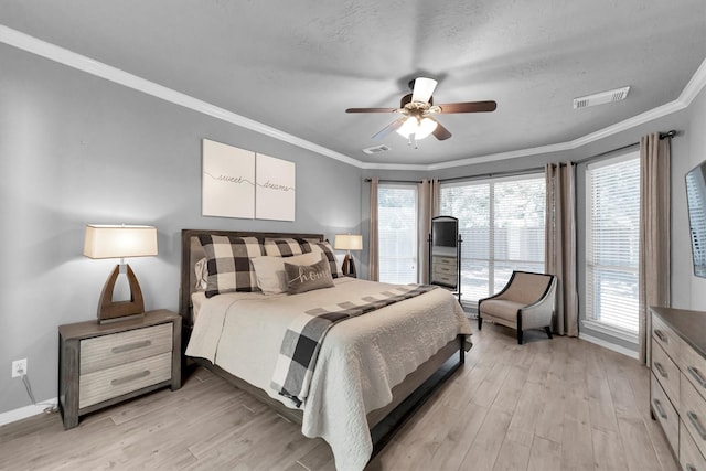 bedroom featuring ceiling fan, visible vents, baseboards, light wood finished floors, and crown molding