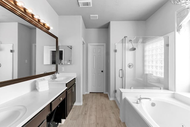 full bath featuring a garden tub, visible vents, a sink, a shower stall, and wood finished floors