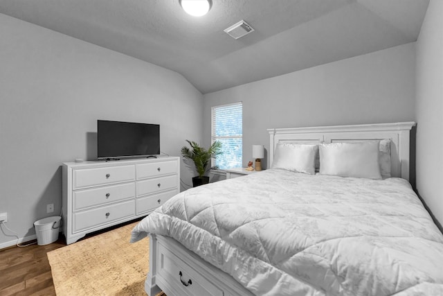 bedroom featuring vaulted ceiling, dark wood-type flooring, visible vents, and baseboards