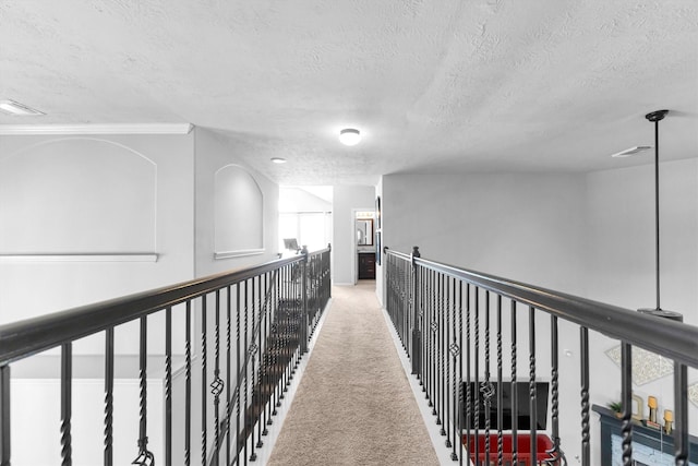 corridor with a textured ceiling, visible vents, and carpet flooring