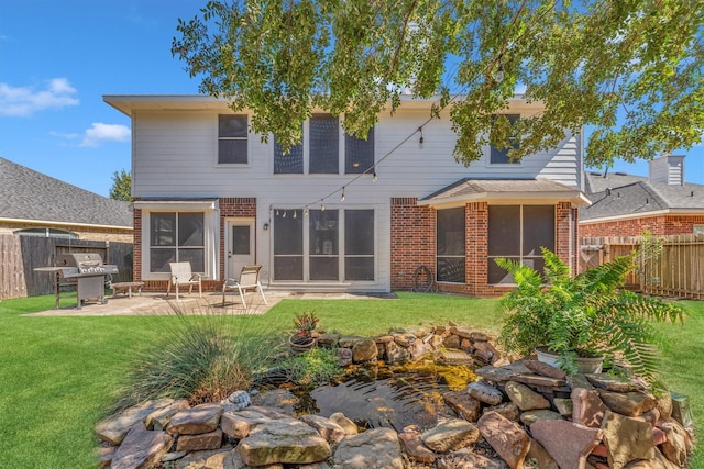 back of house featuring a fenced backyard, a lawn, and brick siding