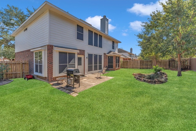 rear view of property with a patio, a fenced backyard, a chimney, a yard, and brick siding