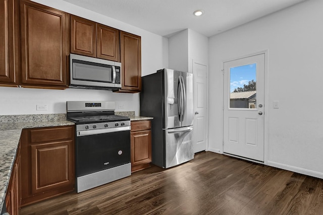 kitchen featuring dark wood finished floors, stainless steel appliances, recessed lighting, light stone countertops, and baseboards