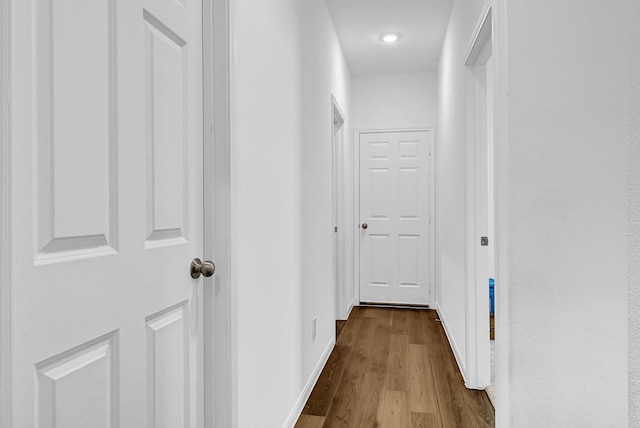 corridor featuring wood finished floors and baseboards