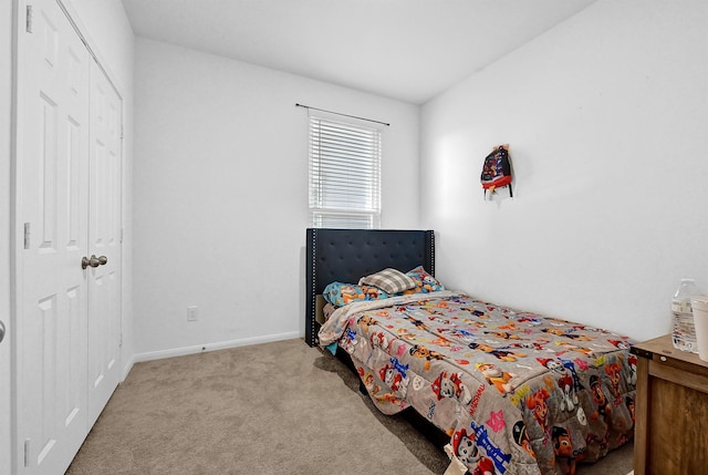 bedroom featuring baseboards, a closet, and light colored carpet