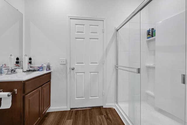 full bathroom featuring a stall shower, wood finished floors, vanity, and baseboards