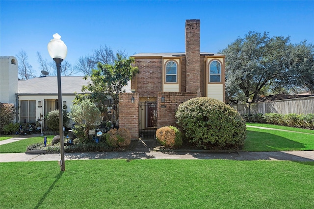 view of front of house featuring a chimney, fence, a front lawn, and brick siding