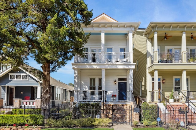 view of front of home with a balcony, ceiling fan, a fenced front yard, and a porch