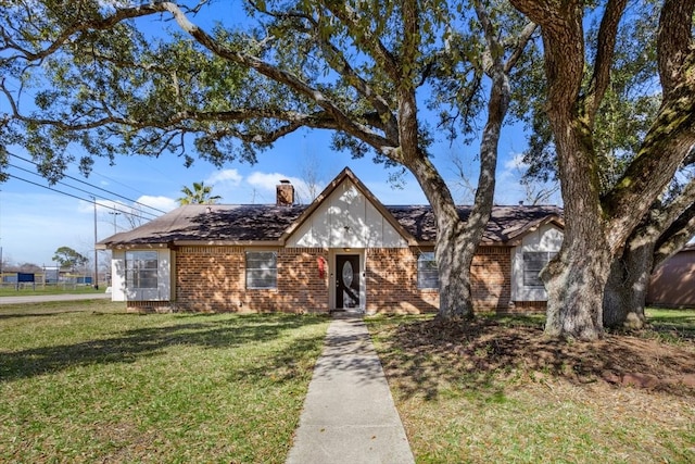 view of front of home with a front yard, brick siding, and a chimney