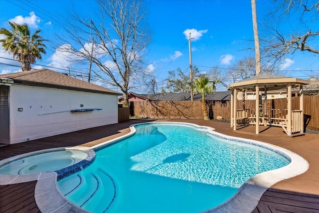 view of swimming pool with a pool with connected hot tub, a fenced backyard, a wooden deck, and a gazebo