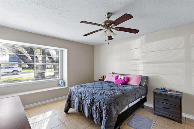 bedroom with a ceiling fan, baseboards, a textured ceiling, and light tile patterned flooring