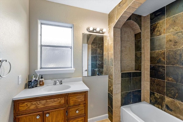 bathroom with a textured wall, bathtub / shower combination, and vanity