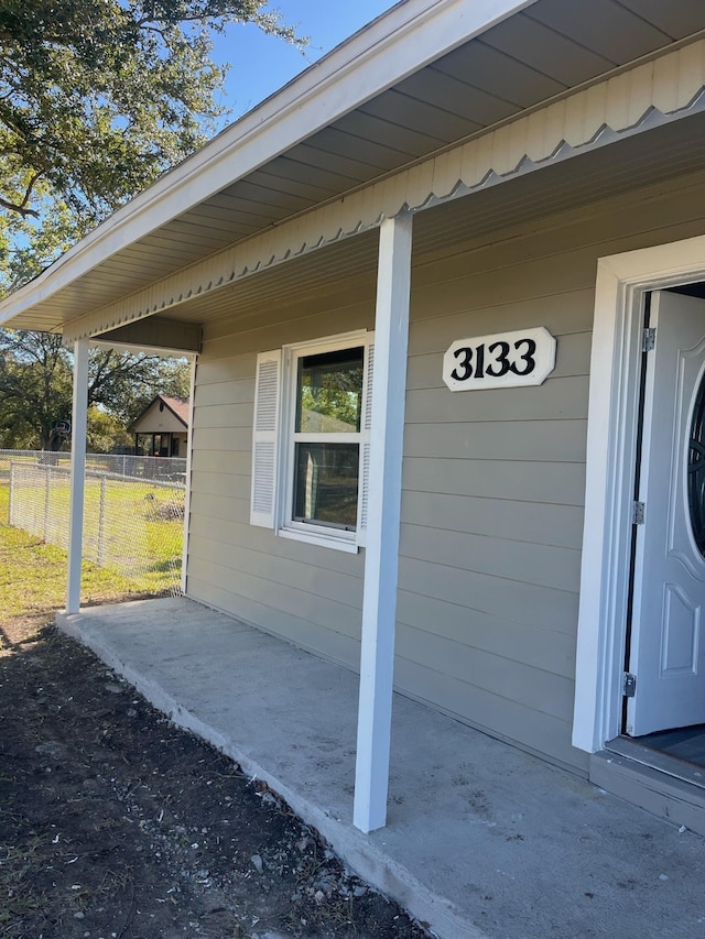 view of exterior entry with a patio area and fence