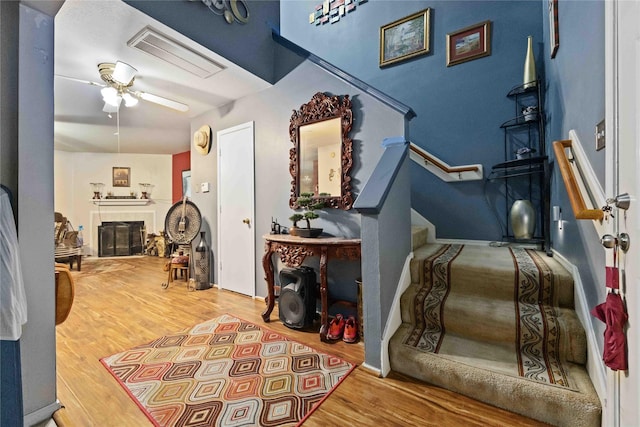 foyer featuring visible vents, a tile fireplace, ceiling fan, stairway, and wood finished floors