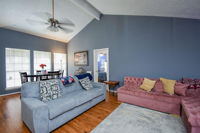 living area featuring vaulted ceiling with beams, ceiling fan, a textured ceiling, and wood finished floors