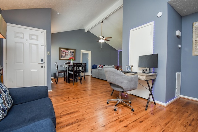 office area featuring baseboards, visible vents, ceiling fan, wood finished floors, and vaulted ceiling with beams