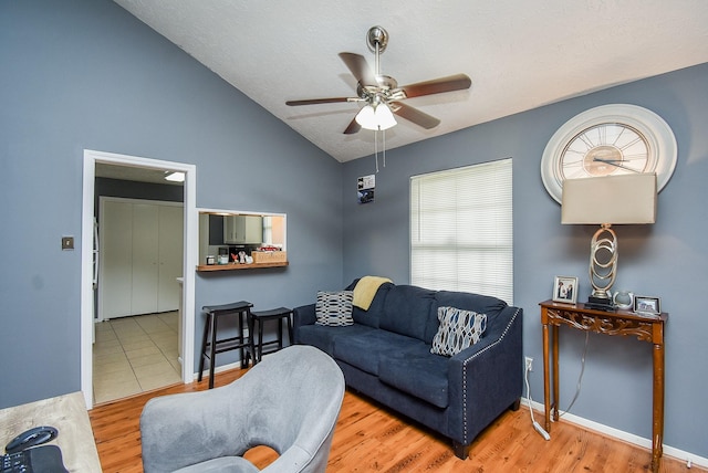 living area with baseboards, a ceiling fan, lofted ceiling, wood finished floors, and a textured ceiling