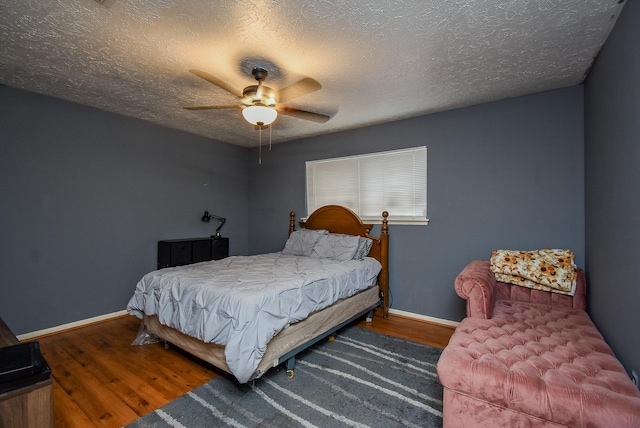 bedroom featuring a ceiling fan, dark wood finished floors, a textured ceiling, and baseboards