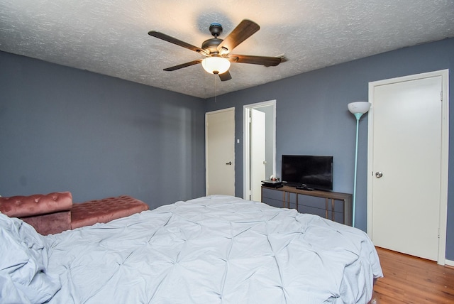 bedroom featuring light wood-style floors, a textured ceiling, and a ceiling fan