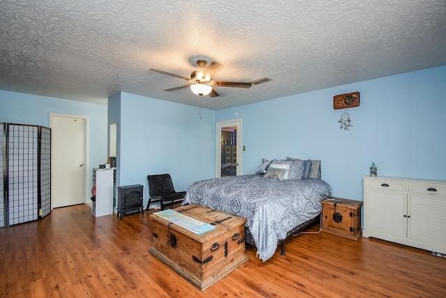 bedroom featuring a textured ceiling, ceiling fan, wood finished floors, and visible vents