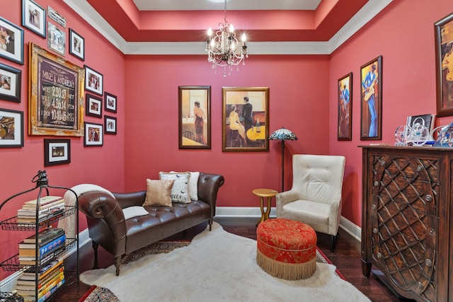 sitting room with a chandelier, a raised ceiling, baseboards, and wood finished floors