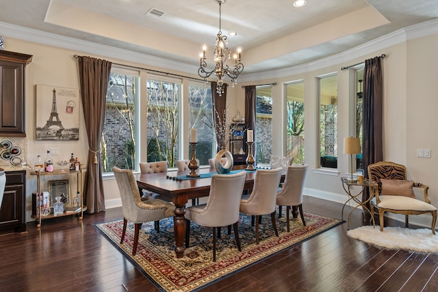 dining area featuring a tray ceiling, dark wood-style flooring, visible vents, and a healthy amount of sunlight