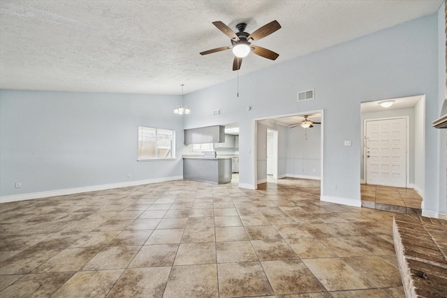 unfurnished living room featuring ceiling fan with notable chandelier, a textured ceiling, light tile patterned flooring, and visible vents