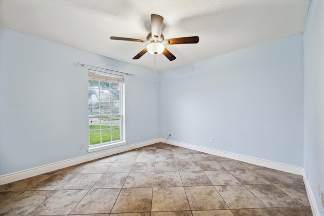 empty room with light tile patterned flooring, ceiling fan, and baseboards