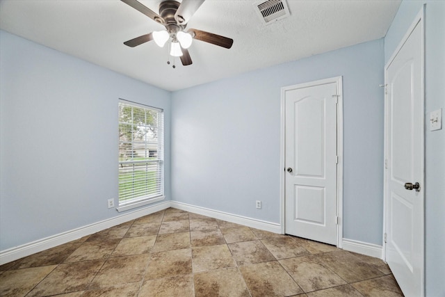 spare room featuring visible vents, ceiling fan, and baseboards