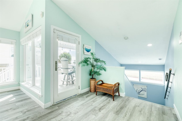 doorway with plenty of natural light, light wood-style flooring, and vaulted ceiling