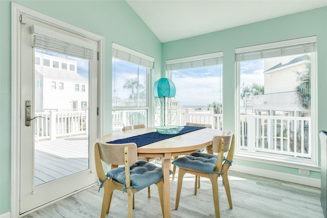 dining space featuring vaulted ceiling, light wood finished floors, and baseboards