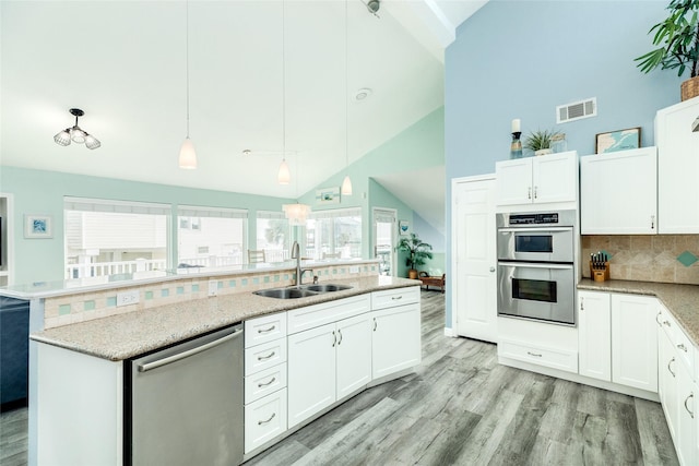 kitchen featuring visible vents, hanging light fixtures, appliances with stainless steel finishes, white cabinetry, and a sink