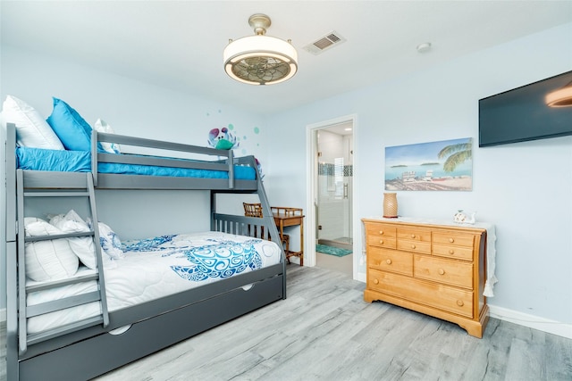 bedroom with light wood-style floors, baseboards, visible vents, and ensuite bathroom