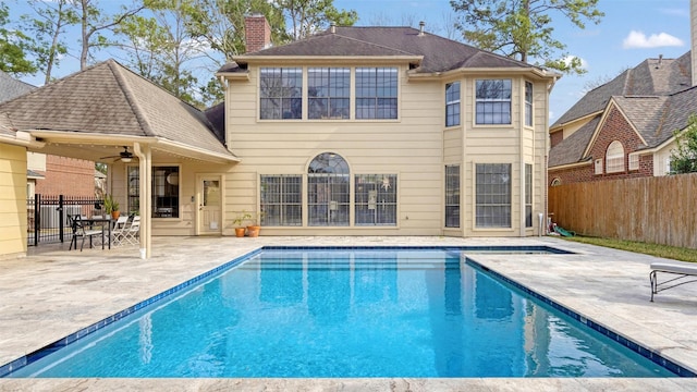 back of property featuring a patio, fence, a ceiling fan, a fenced in pool, and a chimney