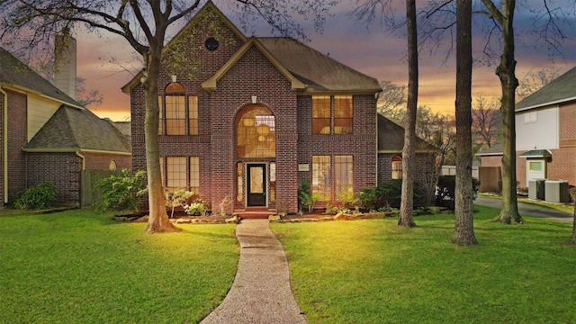 view of front of property with a front lawn, central AC, and brick siding