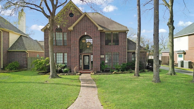 view of front of property featuring central AC, a front lawn, a shingled roof, and brick siding