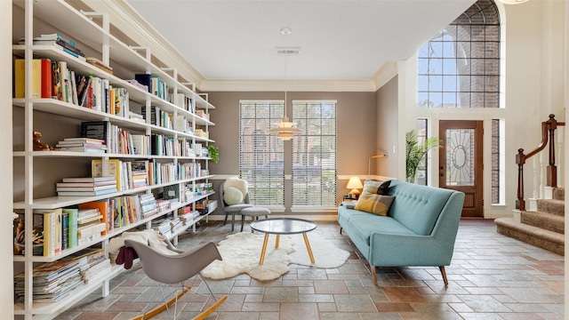 sitting room with stairs, ornamental molding, visible vents, and stone tile floors