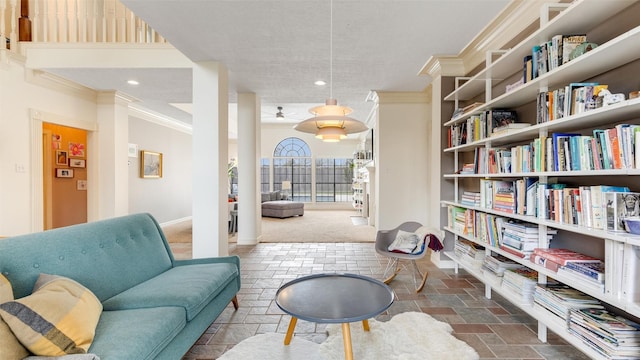 living area with baseboards, stone tile flooring, and crown molding