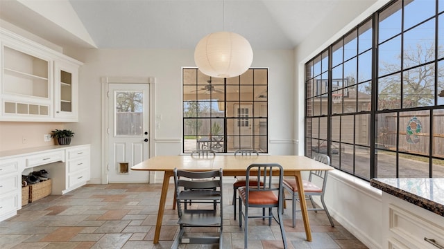 dining room with lofted ceiling, plenty of natural light, baseboards, and stone tile flooring