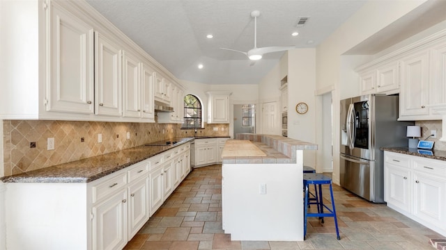 kitchen featuring ceiling fan, a breakfast bar, visible vents, stainless steel refrigerator with ice dispenser, and a center island