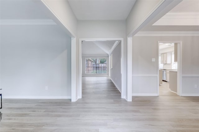 hallway featuring light wood-style floors, crown molding, and baseboards