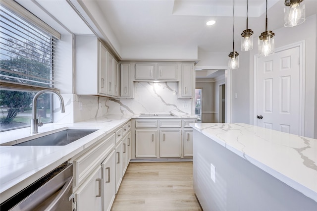 kitchen featuring decorative backsplash, light stone counters, hanging light fixtures, stainless steel dishwasher, and a sink